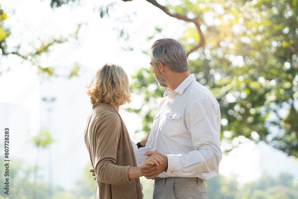 Obraz premium Elderly couple lifestyle concept. Husband embrace wife and sit on seat in the park relax on retirement life.