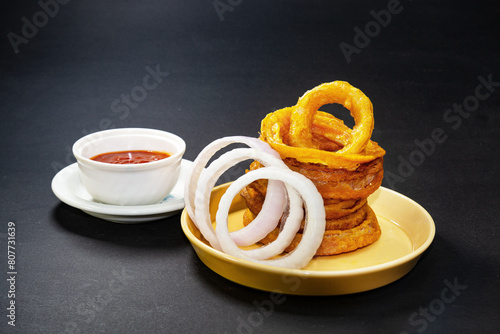 Homemade crunchy fried onion rings with tomato sauce and raw onion slices.