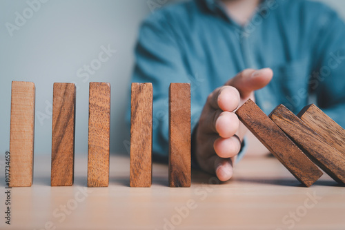 Businessman hand obstruct rectangle  block which falling to stop dominos others rectangle standing for risk assessment and crisis management concept.