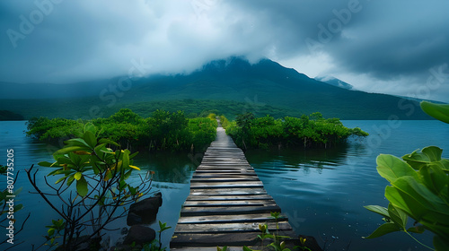 A wooden bridge leads to the mountain, with green vegetation on both sides and water in front. The sky is a dark blue, with some white clouds