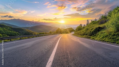 Sunrise view of a mountainous landscape and a paved road.