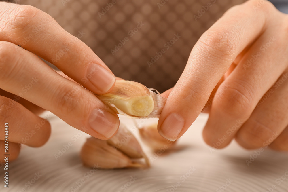Woman peeling fresh garlic at table, selective focus Woman peeling fresh garlic at table, selective focus