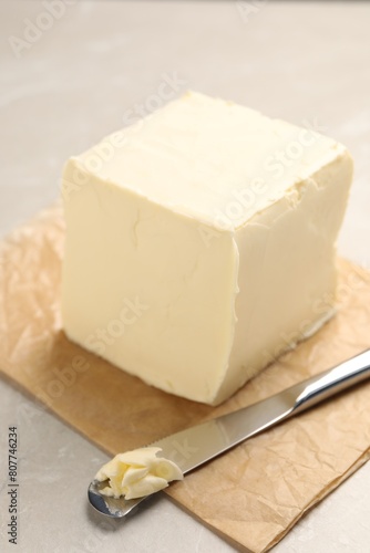 Block of tasty butter and knife on light table