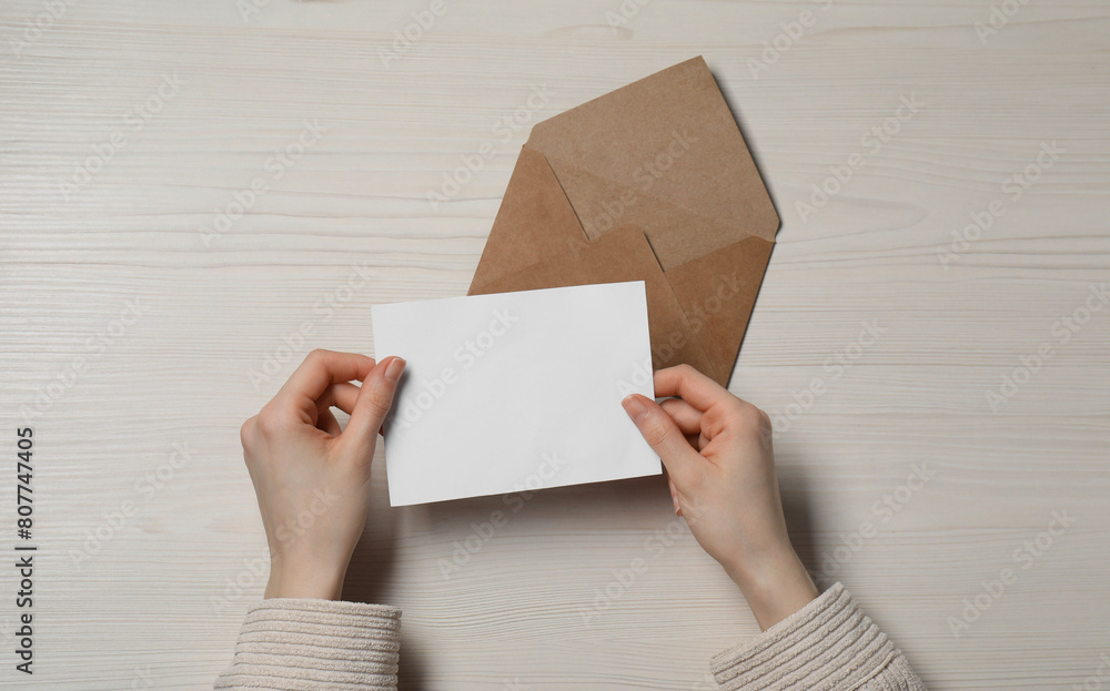 Woman with blank card at light wooden table, top view. Space for text Woman with blank card at light wooden table, top view. Space for text