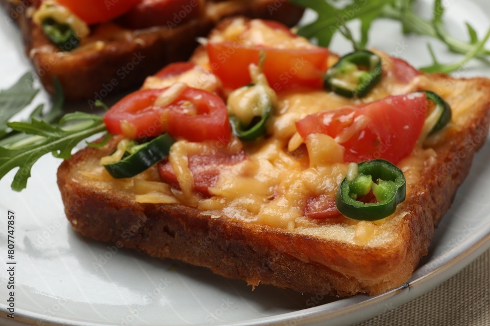 Tasty pizza toast and fresh arugula on plate, closeup