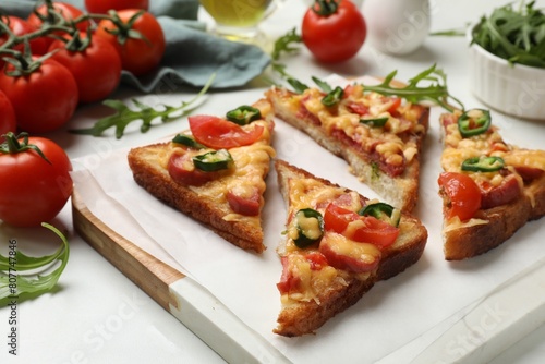 Tasty pizza toasts and ingredients on white marble table, closeup