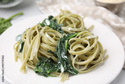 Tasty pasta with spinach and sauce on white table, closeup