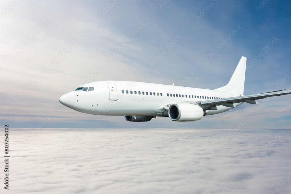White passenger jetliner flying in the air above the clouds