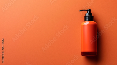 A blank cosmetic cream bottle on the right side of a solid orange background with copyspace on the left