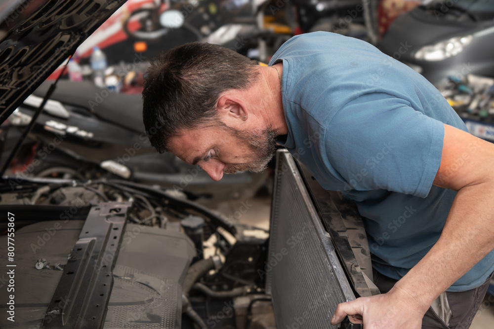 Mechanic Installing Radiator in Car at Auto Repair Shop Mechanic Installing Radiator in Car at Auto Repair Shop