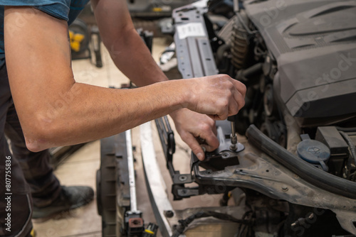 Mechanic Tightening Bolts on Car Engine at Repair Shop