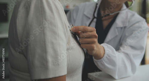 Doctor using sphygmomanometer with stethoscope checking blood pressure to a patient in the hospital.