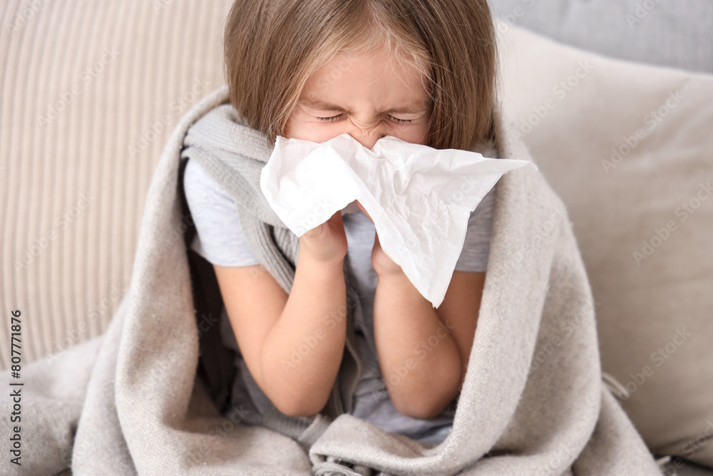 Sick little girl with tissue sneezing on sofa at home, closeup Sick little girl with tissue sneezing on sofa at home, closeup