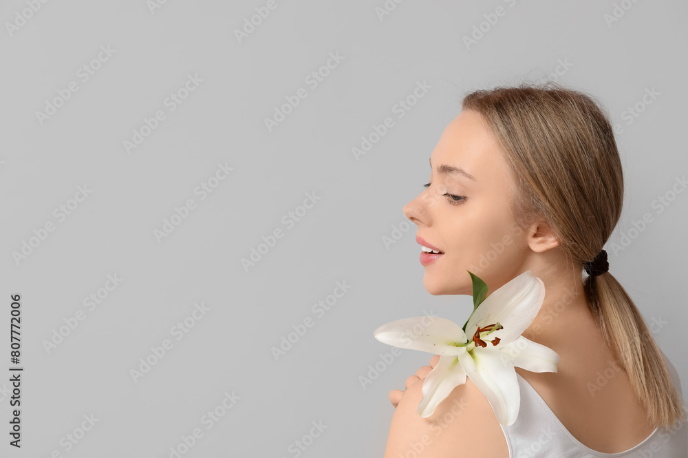 Beautiful young woman with lily flower on grey background Beautiful young woman with lily flower on grey background