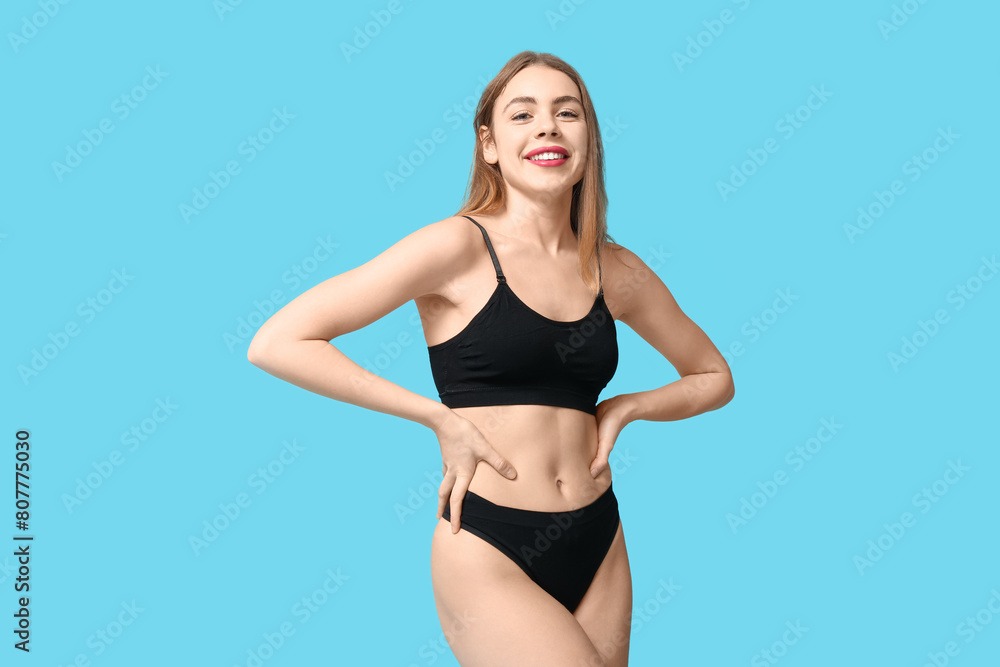 Fototapeta premium Sexy young woman in black cotton underwear on blue background