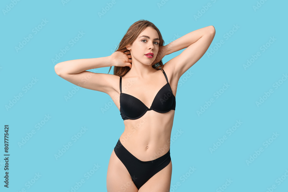 Obraz premium Attractive young woman in black underwear on blue background