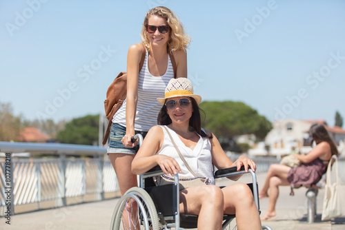 invalid girl on the wheelchair with friend outdoors