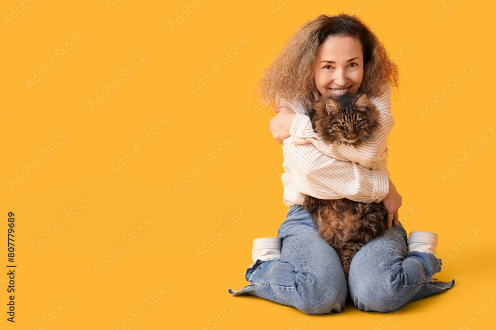 Mature woman with cute cat on yellow background Mature woman with cute cat on yellow background