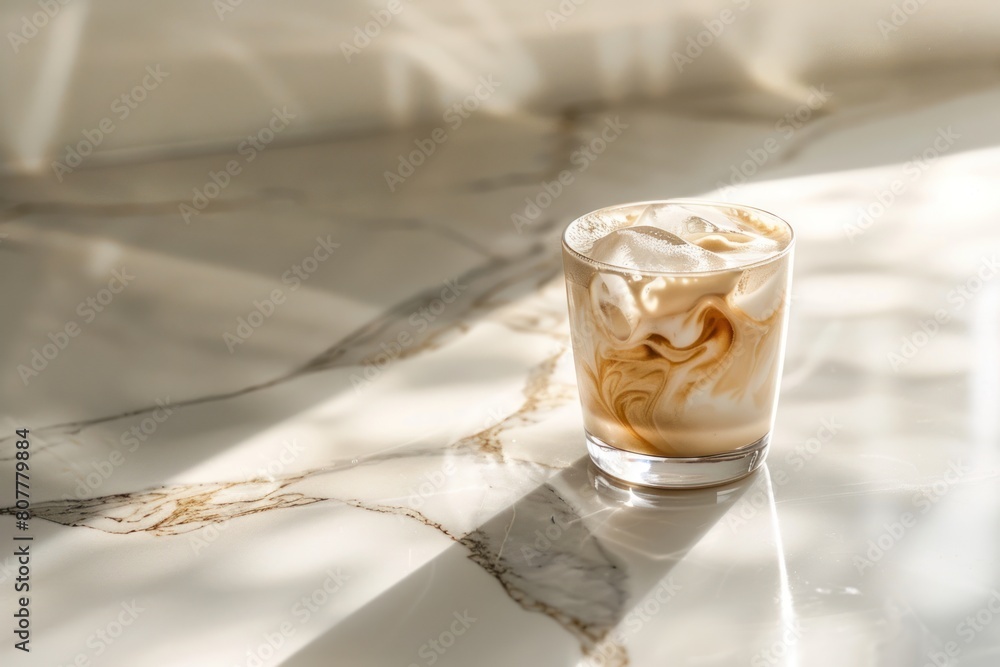 A glass of coffee sits on a marble countertop. The coffee is creamy and has a light brown color A glass of coffee sits on a marble countertop. The coffee is creamy and has a light brown color