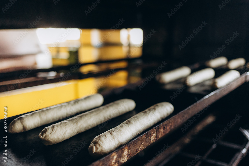 white round pastry dough arranged in a row in a stainless steel tray Putting into a large baking oven, the baking concept white round pastry dough arranged in a row in a stainless steel tray Putting into a large baking oven, the baking concept