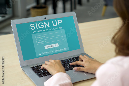 Foto Back view of businesswoman in suit engrossed in creating her identity online, registering for an account on laptop computer