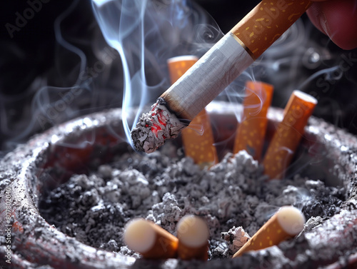 A smoker puts out a cigarette in a full ashtray, showing their effort to quit smoking. It symbolizes the desire to kick the habit.