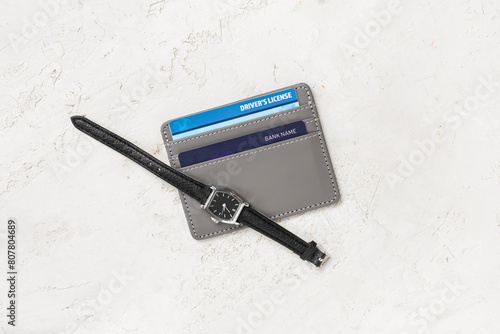Watches, grey credit holder with cards and driver's license on light background, closeup