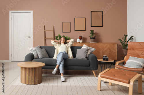 Young pretty woman resting on sofa in beige living room photo