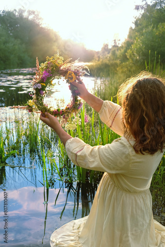 girl with flower wreath stand in river. summer nature background. Floral crown, symbol of summer solstice. ceremony for Midsummer, wiccan Litha sabbat. pagan folk holiday Ivan Kupala