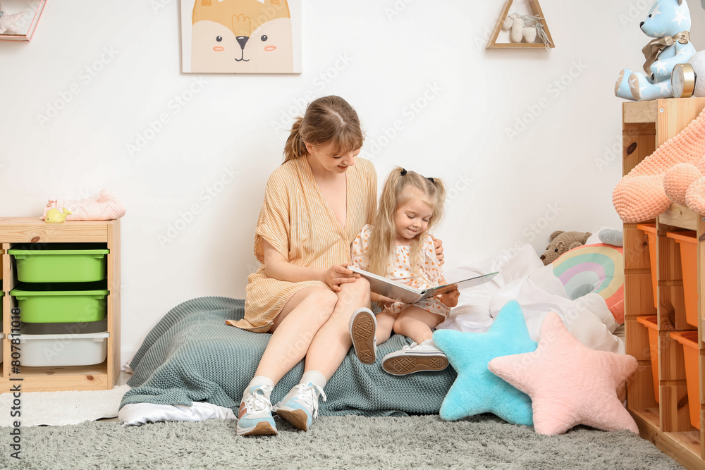 Naklejka premium Nanny with little girl reading story in bedroom