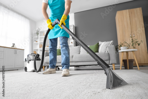 Male janitor cleaning carpet in room photo