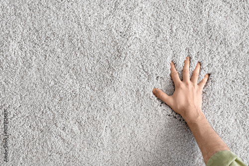 Obraz na plátně Male hand on soft carpet, top view