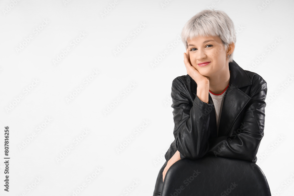 Stylish young woman in leather jacket with chair on light background Stylish young woman in leather jacket with chair on light background