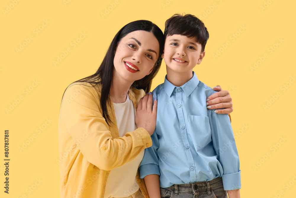 Mother hugging her little son on yellow background Mother hugging her little son on yellow background