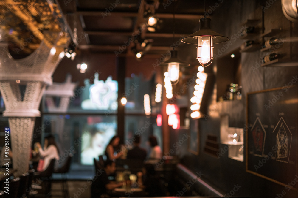 Fototapeta premium Dimly lit bar with hanging lights and relaxed patrons