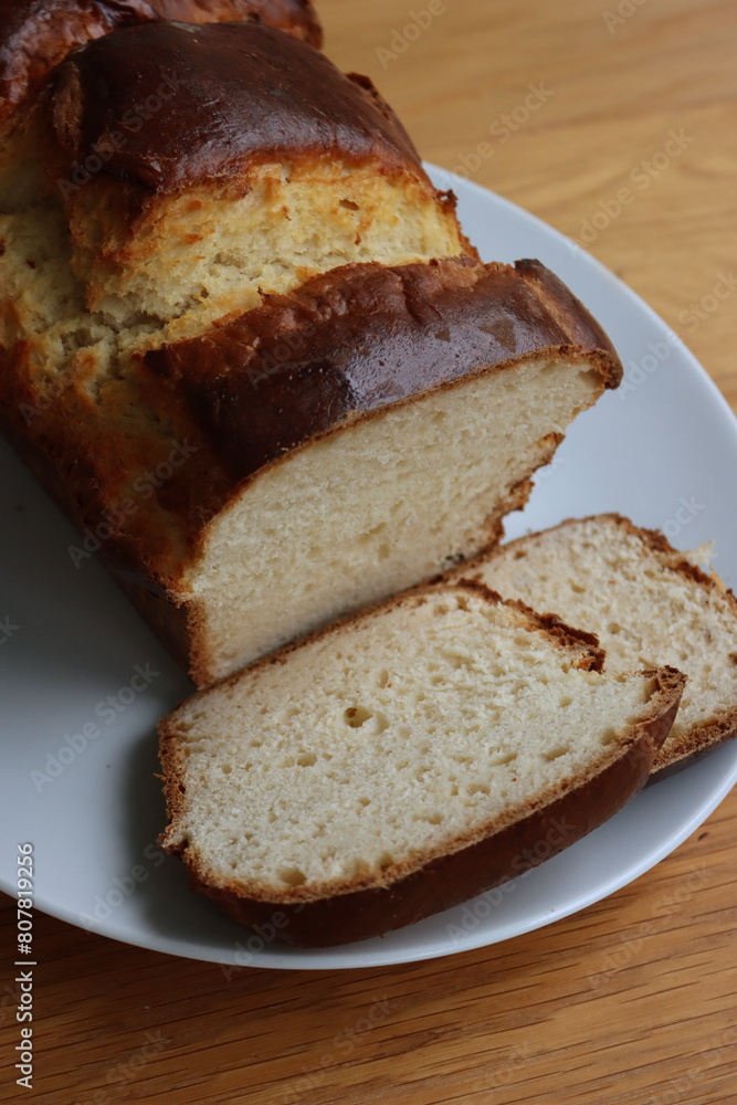 Homemade baked and sliced Brioche Bread on a white plate on wooden table Homemade baked and sliced Brioche Bread on a white plate on wooden table