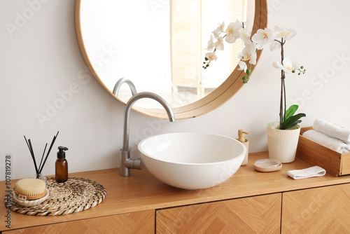 Wooden cabinet with sink, mirror and bathing accessories in stylish bathroom