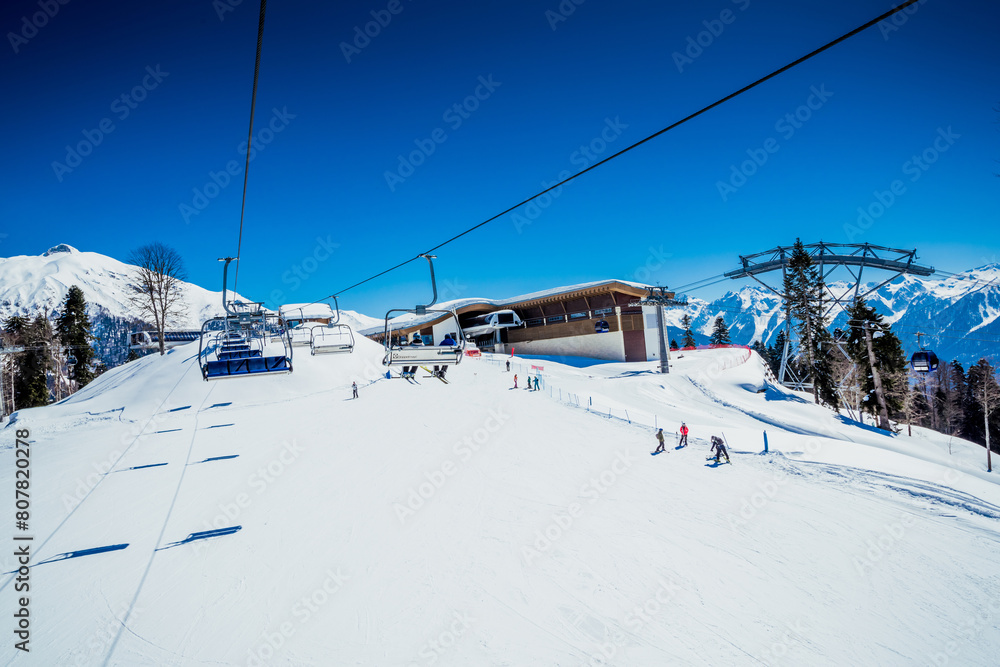 Ski slopes with cable car tracks and a metal support from a freeride track with untouched snow under a clear blue sky. KRASNAYA POLYANA, SOCHI, RUSSIA – winter JANUARY: «Laura». Ski slopes with cable car tracks and a metal support from a freeride track with untouched snow under a clear blue sky. KRASNAYA POLYANA, SOCHI, RUSSIA – winter JANUARY: «Laura».