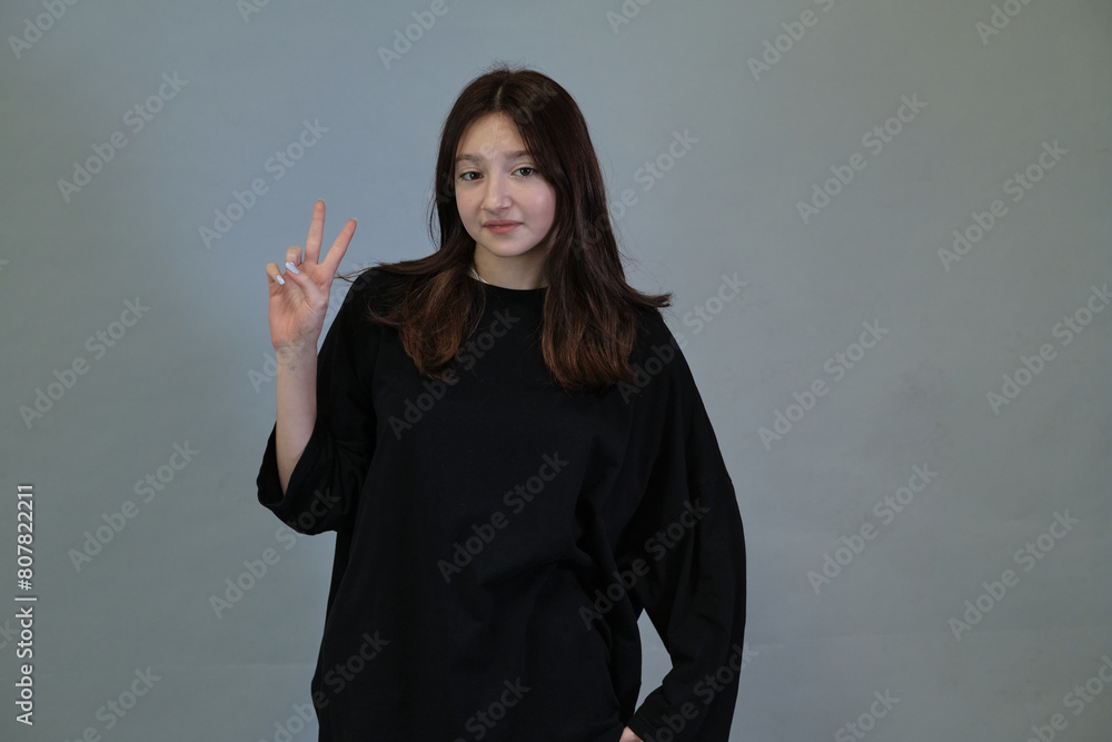 Relaxed girl posing with a peace hand signal, capturing the laid-back style of the digital generation. Symbolizes a carefree attitude. Relaxed girl posing with a peace hand signal, capturing the laid-back style of the digital generation. Symbolizes a carefree attitude.