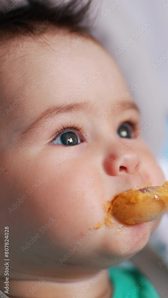 Nice kid eating porridge from spoon. Adorable toddler sticks out tongue and waves his hands. Close up. Vertical video Nice kid eating porridge from spoon. Adorable toddler sticks out tongue and waves his hands. Close up. Vertical video