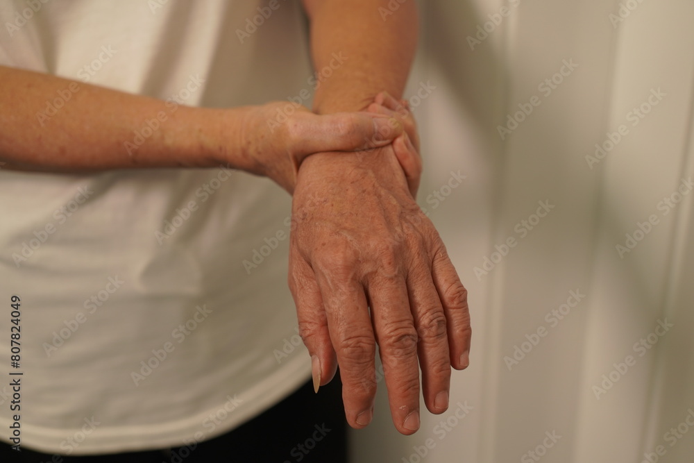 A woman uses her other hand to feel pain. and tingling along with symptoms of numbness in the hands Elderly woman tries to massage herself to relieve wrist pain A woman uses her other hand to feel pain. and tingling along with symptoms of numbness in the hands Elderly woman tries to massage herself to relieve wrist pain