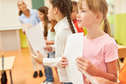 Girl singing during choir practice with classmates