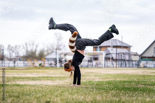 Teenage girl with cat mask and gloves doing Quadrobics. girl in a cat mask Jumps like a cat. the athlete is standing on her hands