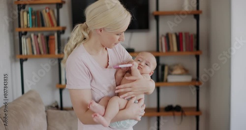 A loving mother holding and rocking her newborn baby boy indoors