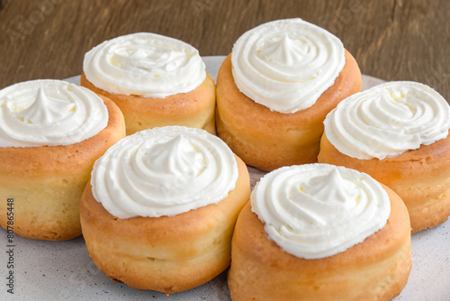 juicy cinnabons.lush round buns with white airy cream on top lie on a white plate, top view, sweet concept photo
