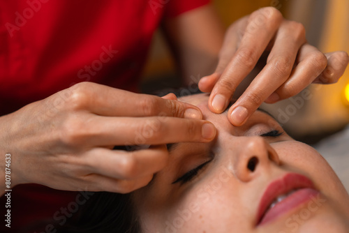 Beautiful young woman receives a tightening facial massage in the technique of pinching in a beauty salon. Masseur does a close-up facial massage