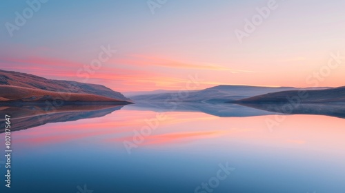 The image shows a beautiful sunset over a lake. The sky is a gradient of orange, pink, and blue, and the water is a deep blue. The image is very peaceful and serene.