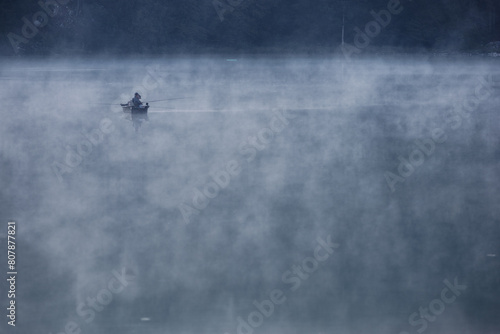 barque avec pêcheurs dans la brume matinale sur le lac Genin dans l'Ain photo