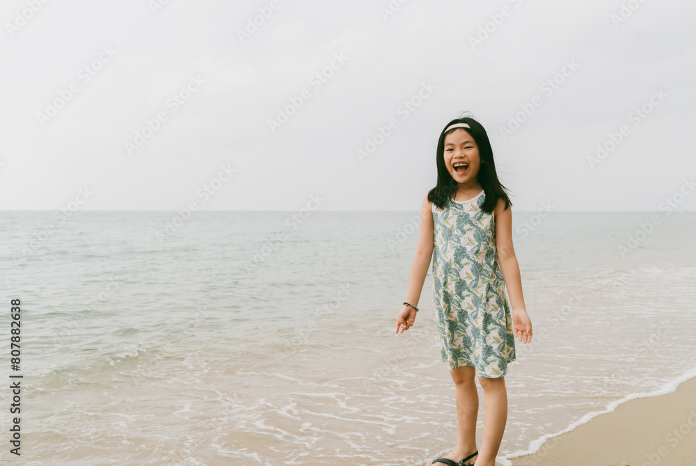 Portrait an Asian happy child girl standing on a beach, shouting happily, bright light image with space. Portrait an Asian happy child girl standing on a beach, shouting happily, bright light image with space.