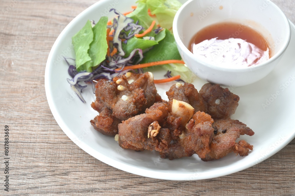 fried crispy pork bone or rib with fresh vegetable on plate dipping chili sauce cup 
